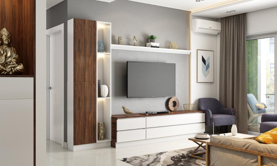 Minimalist living room featuring a wooden TV unit, open shelves, grey accent wall and simple furnishings.